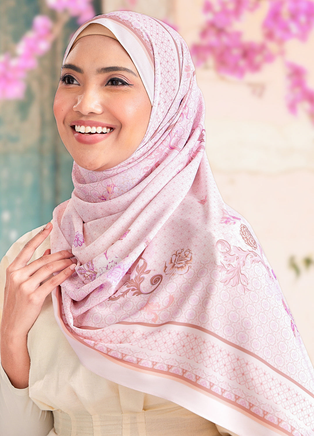 Woman wearing a pink hijab with floral patterns against a blurred background