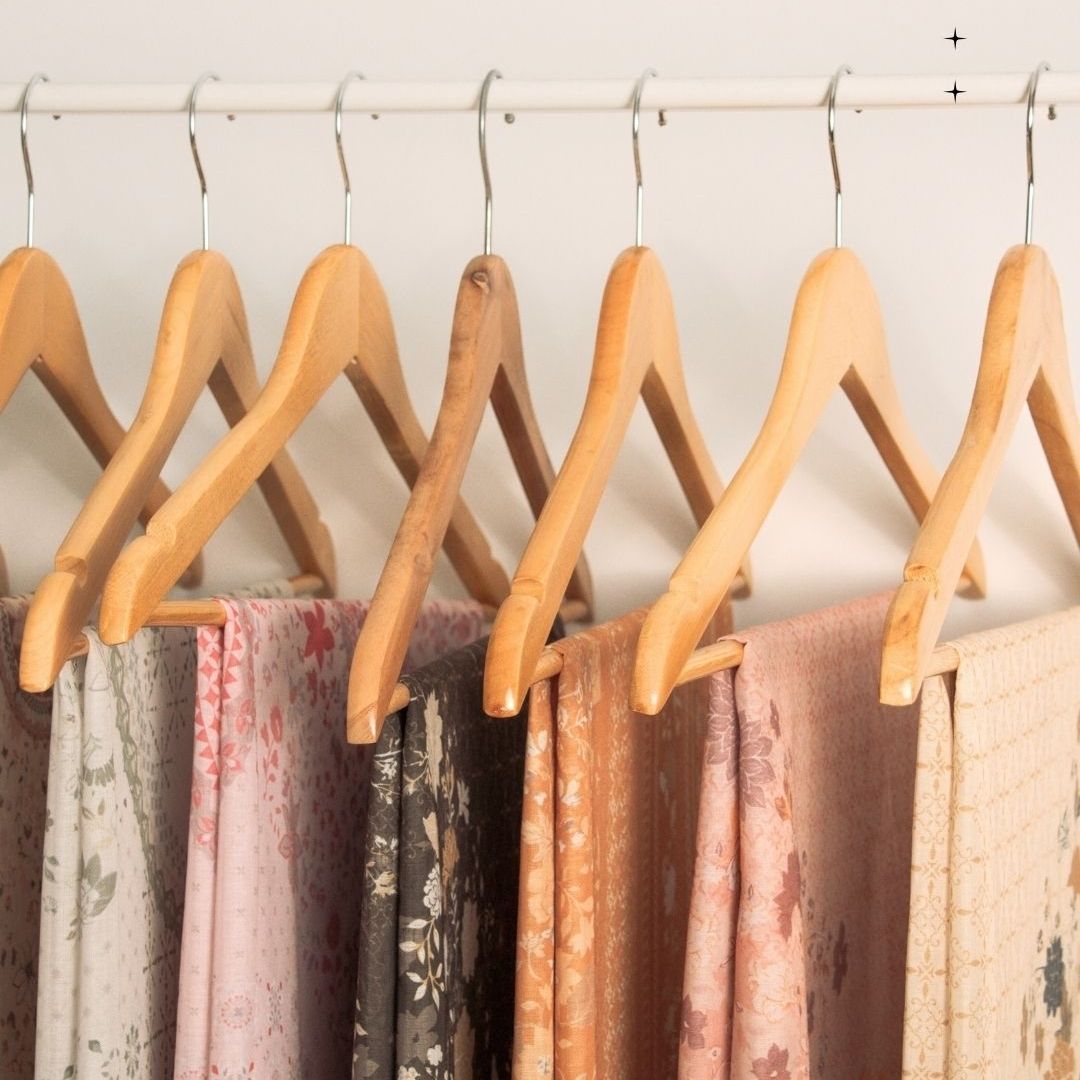 Wooden hangers with scarves on a white wall