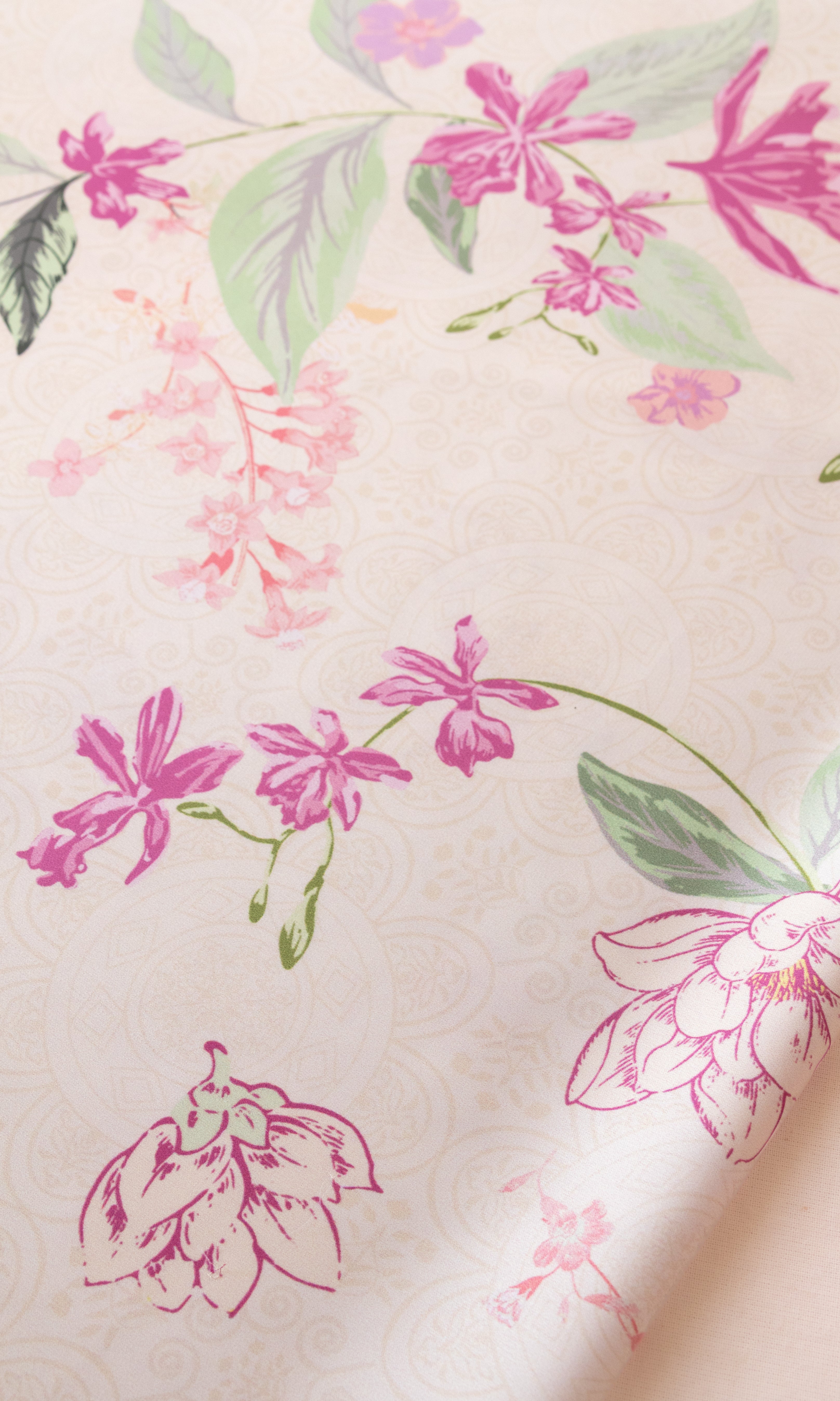 A close-up of a cream-colored fabric or wallpaper featuring a delicate floral pattern with pink flowers and green leaves.