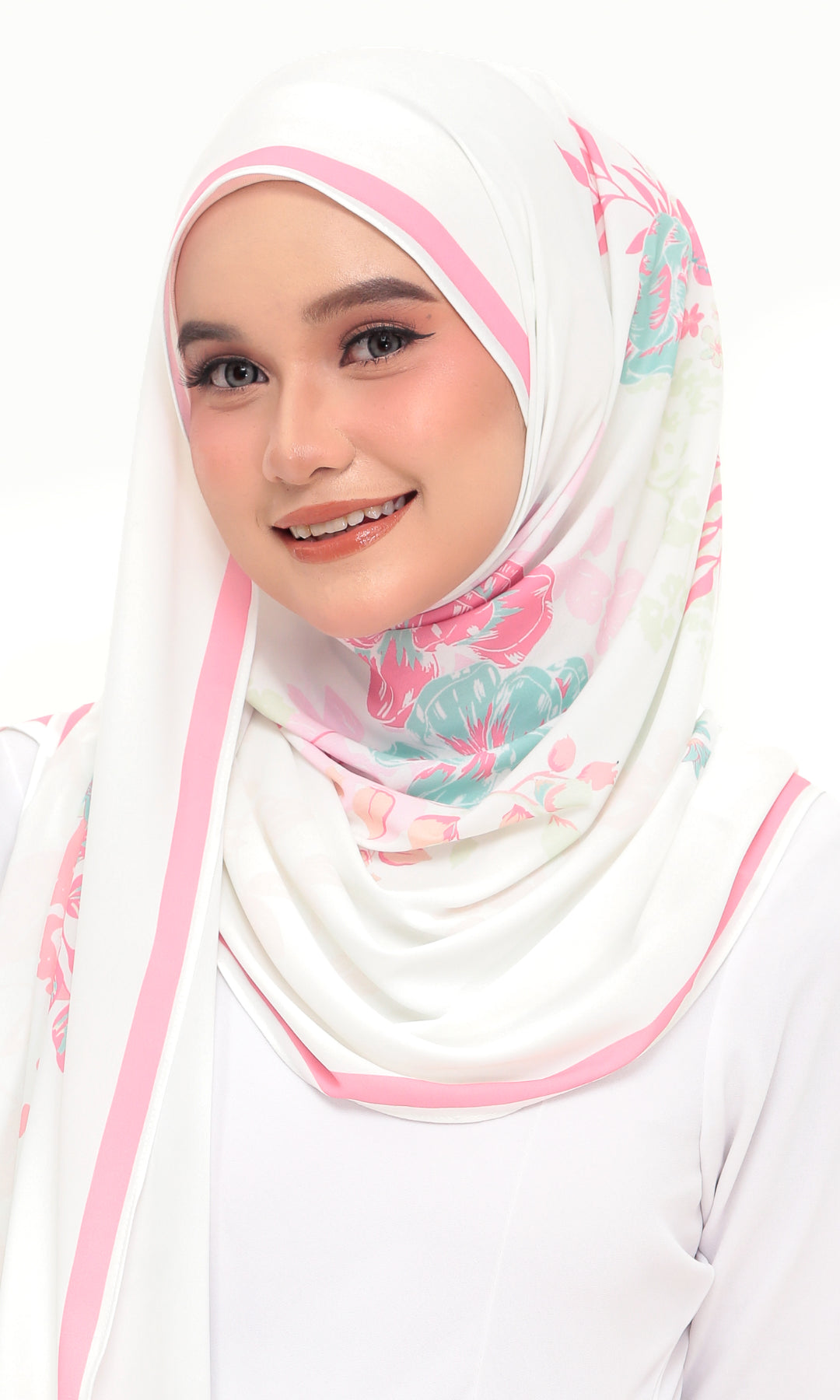 A woman wearing a white hijab with pink stripes and a pink, teal, and green floral print, paired with a white top against a plain white background.