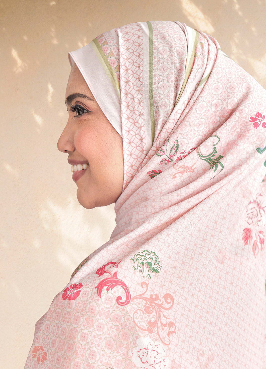 Woman wearing a pink hijab with floral patterns on a beige background