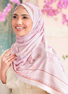 Woman wearing a pink hijab with floral patterns against a blurred background