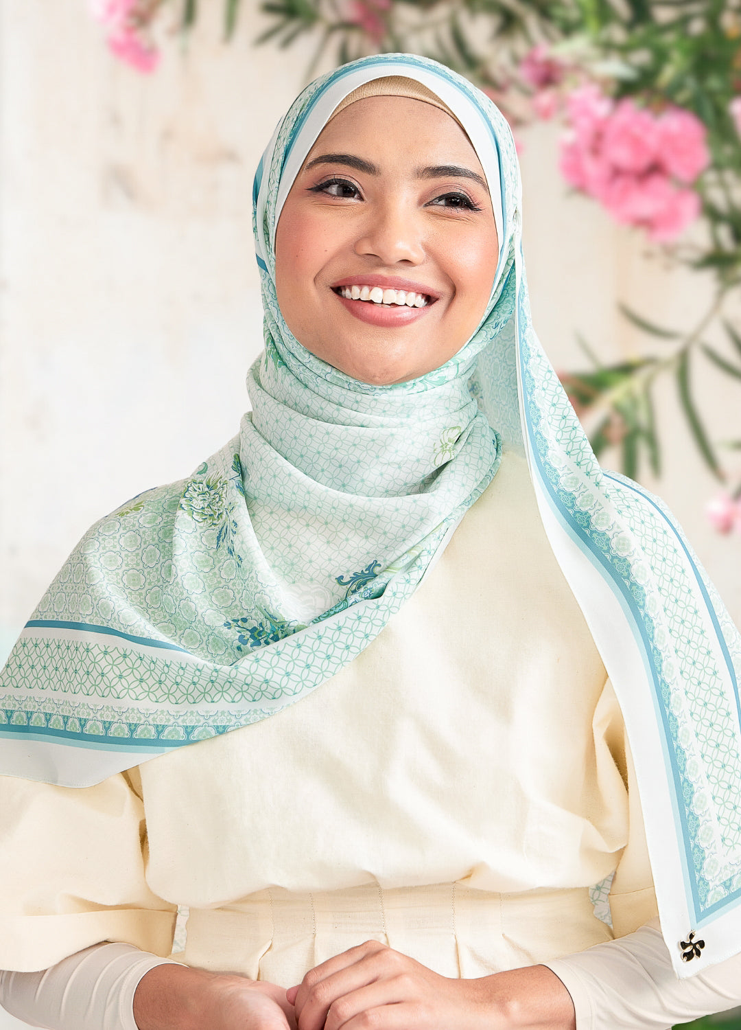 Woman wearing a light blue hijab with floral background