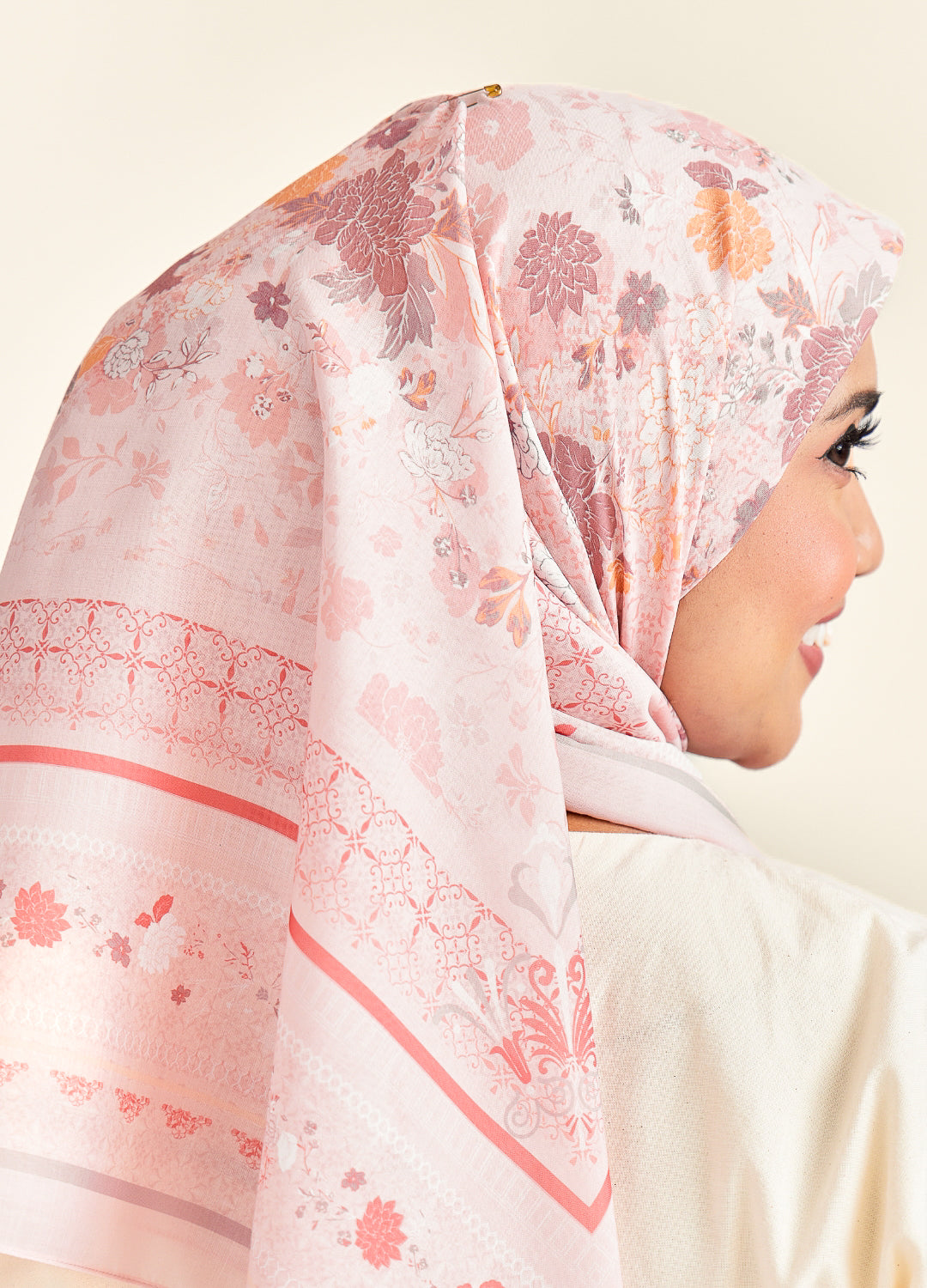 Woman wearing a floral hijab with pink and orange patterns on a light background