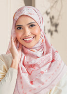 Woman wearing a pink hijab with floral patterns, smiling against a neutral background