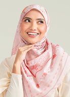 Woman wearing a pink hijab with floral patterns on a light background