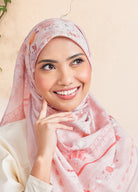 Woman wearing a pink hijab with floral patterns on a beige background