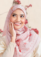 Woman wearing a pink floral hijab with a blurred floral background