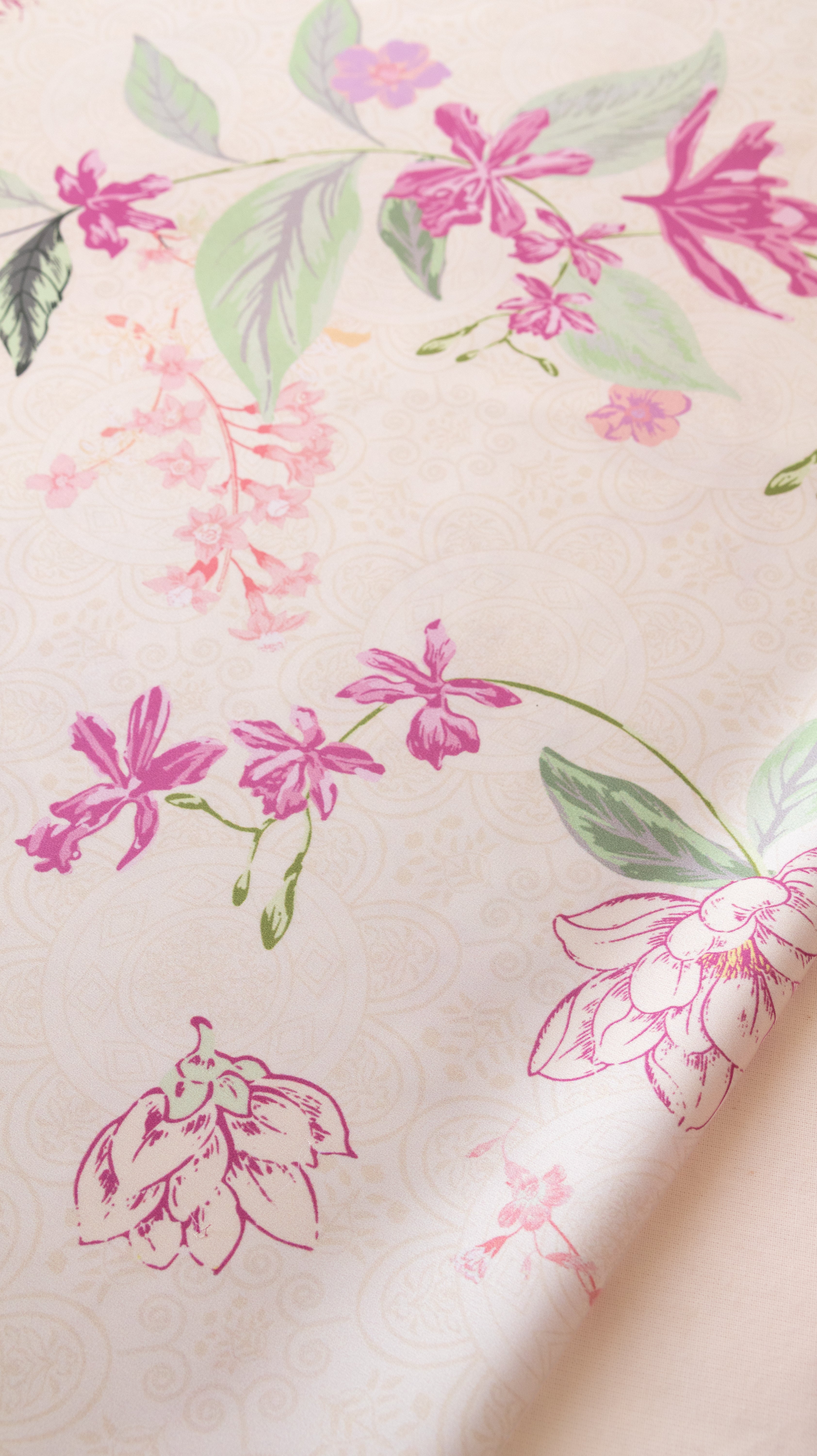 A close-up of a cream-colored fabric or wallpaper featuring a delicate floral pattern with pink flowers and green leaves.