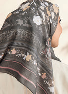 Floral patterned scarf draped over a person's head with a neutral background