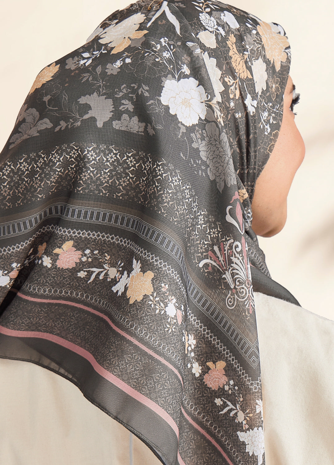 Floral patterned scarf draped over a person's head with a neutral background