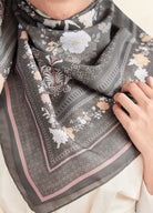 Gray floral patterned scarf being held by a person