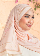 Woman wearing a pink hijab with floral patterns against a soft, blurred background