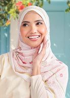 Woman wearing a pink hijab with floral patterns against a light blue background
