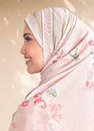 Woman wearing a pink hijab with floral patterns on a beige background