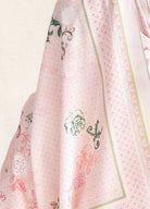 Close-up of a pink fabric with green floral patterns on a light background